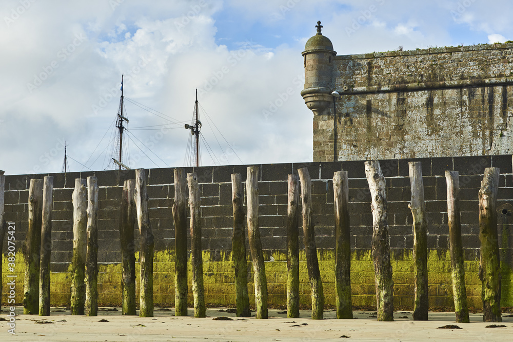 Fototapeta premium Wooden Poles and rampart on the beach at low tide in Saint Malo, Brittany, France