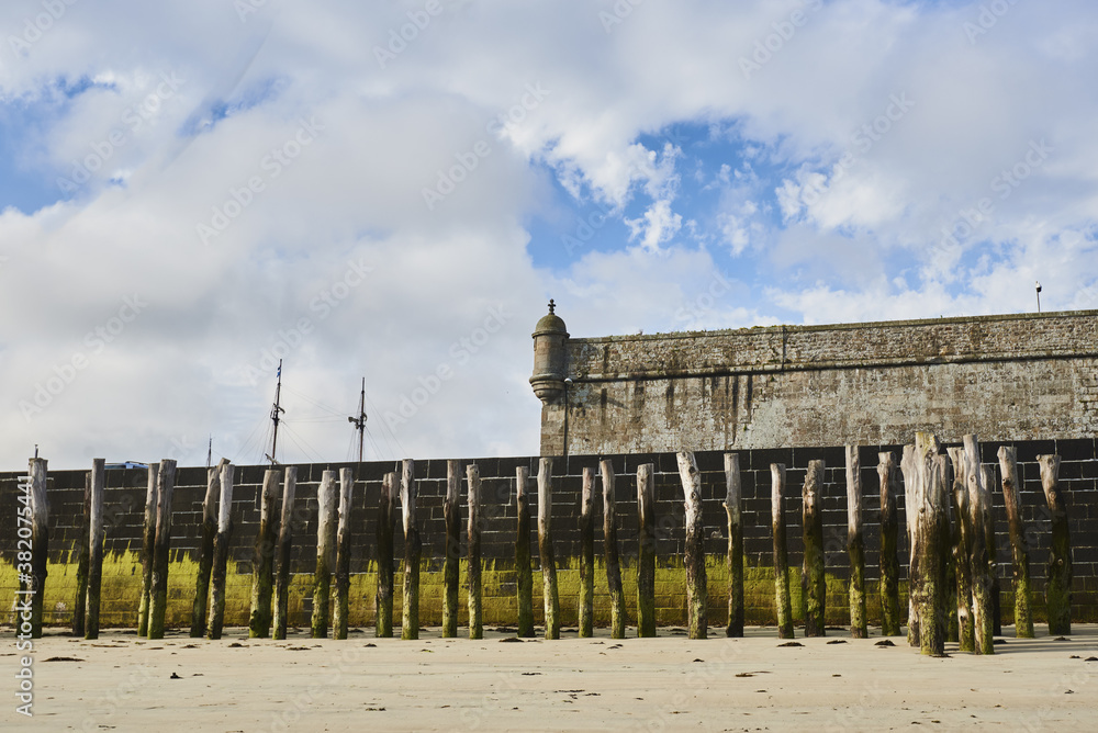 Wooden Poles and rampart on the beach at low tide in Saint Malo, Brittany, France Wooden Poles and rampart on the beach at low tide in Saint Malo, Brittany, France