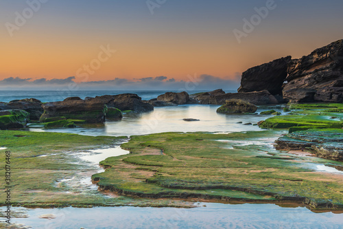 Winter sunrise seascape with green mossy rock platform