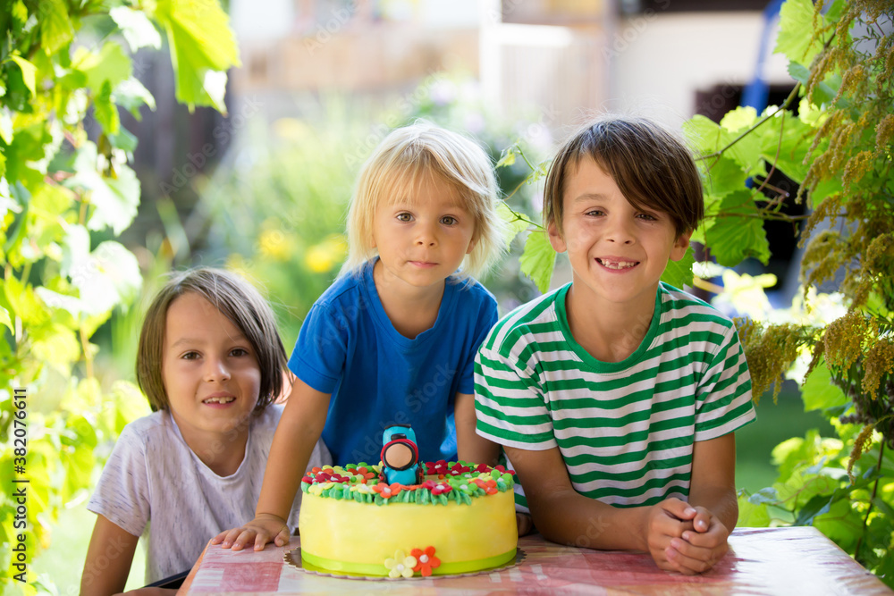 Toddler boy, celebrating his birthday with brothers and family outdoors Toddler boy, celebrating his birthday with brothers and family outdoors