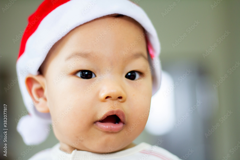 little baby smile Cute celebrates Christmas. New Year's holidays. Asia Baby in a Christmas Santa hat on soft fabric little baby smile Cute celebrates Christmas. New Year's holidays. Asia Baby in a Christmas Santa hat on soft fabric