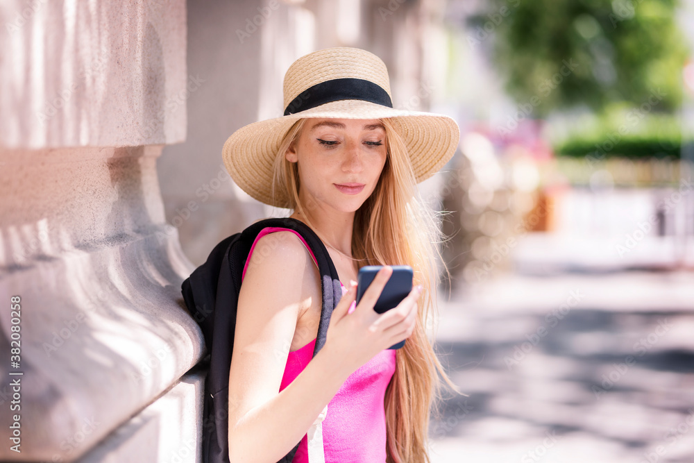 Smiling young woman text messaging while standing on the street