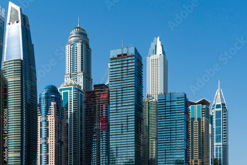 Tops of glass and steel skyscrapers of financial district of Dubai, UAE at sunny day. Building exteriors of the capital of the Emirate of Dubai. A trading international hub of Western Asia.