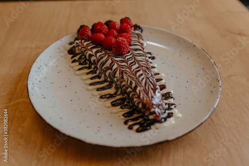 chocolate pancake with bananas, nuts and chocolate sauce. the toning. selective focus. a rolled chocolate pancake is a calorie bomb photo