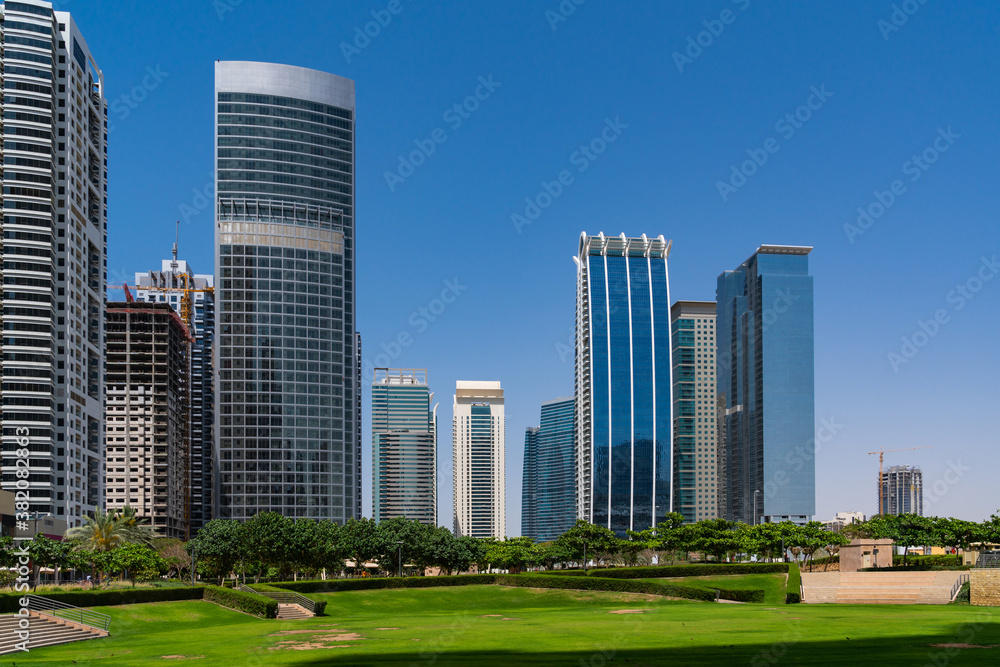Looking along grassland towards the skyline of financial area of Dubai at sunny day. Dubai is the most popular city in the United Arab Emirates UAE and the capital of the Emirate of Dubai.