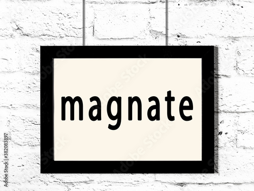 Valokuva Black frame hanging on white brick wall with inscription magnate