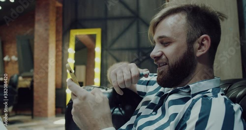 man with a beard, uses the phone and smokes electronic cigarette.