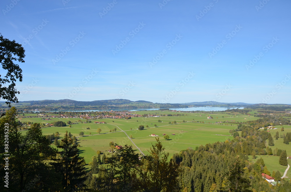 View from Neuschwanstein Castle to the flat lakeland behind it with a sunny clear blue sky 