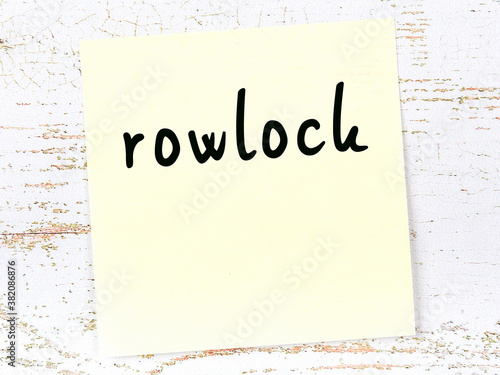 Yellow sticky note on wooden wall with handwritten word rowlock photo