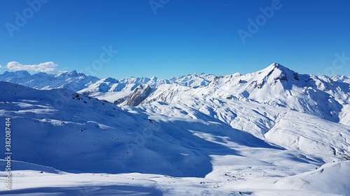Sunny view over the peaks of white mountains of the French Alps from the ski area Les Trois Valless with clear blue sky © Luca Schmidt
