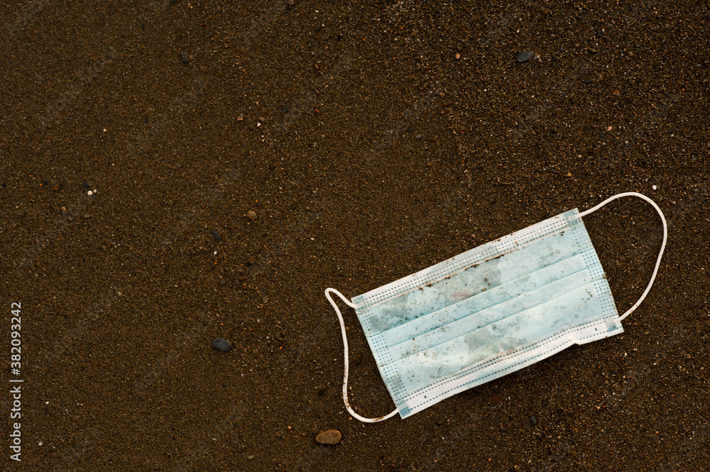 Waste during COVID-19 with sand in the background. Dumped into oceanic coronavirus single-use face masks. Environmental and coastal plastic pollution. Garbage on the beach Waste during COVID-19 with sand in the background. Dumped into oceanic coronavirus single-use face masks. Environmental and coastal plastic pollution. Garbage on the beach