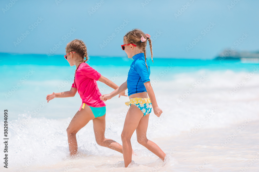Two little happy girls have a lot of fun at tropical beach playing together