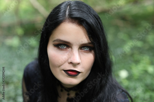 Photography Portrait of spooky young woman with long black hair, blue eyes and dark makeup
