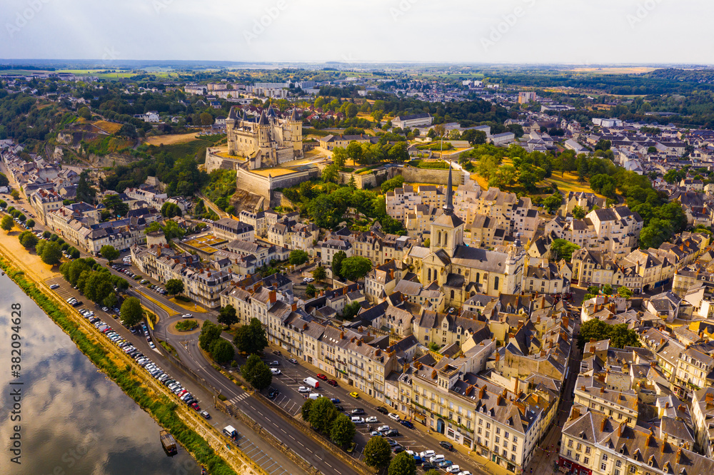 Drone view of ancient Chateau de Saumur and church of St. Peter with cityscape on background on sunny summer day, France