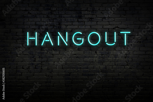 Night view of neon sign on brick wall with inscription hangout photo