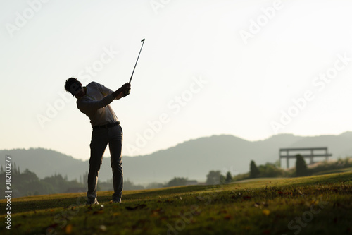 Golfer he's golfing in sunlight of the morning. View from the back. Silhouette of Golfer.