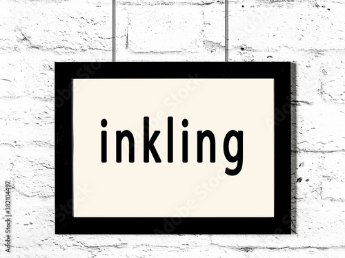 Black frame hanging on white brick wall with inscription inkling