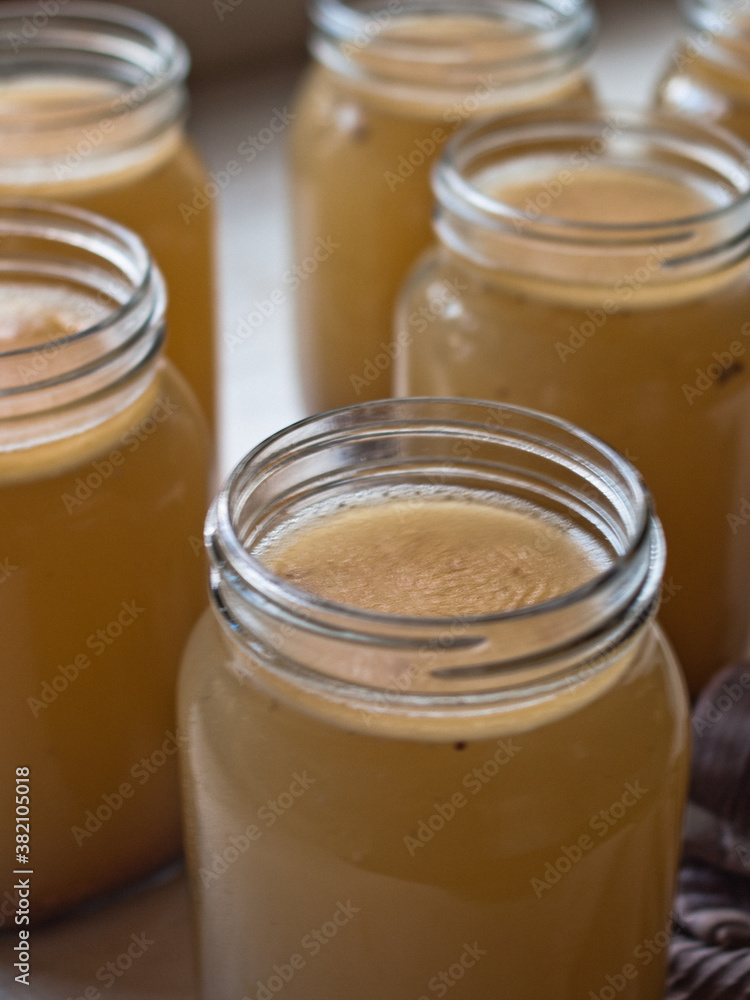 Home made bone broth in glass jars on kitchen table. Natural light. Home made bone broth in glass jars on kitchen table. Natural light.
