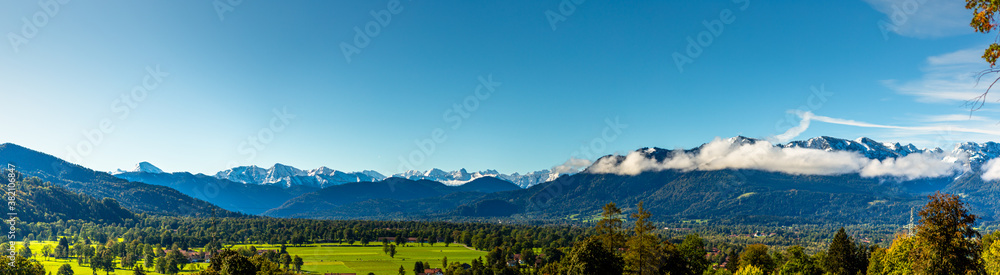 Green meadow field, snow covered mountain range. European Alps at bad toelz Brauneck. Isartal Valley