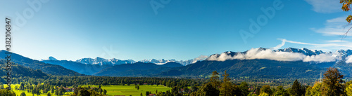 Green meadow field, snow covered mountain range. European Alps at bad toelz Brauneck. Isartal Valley