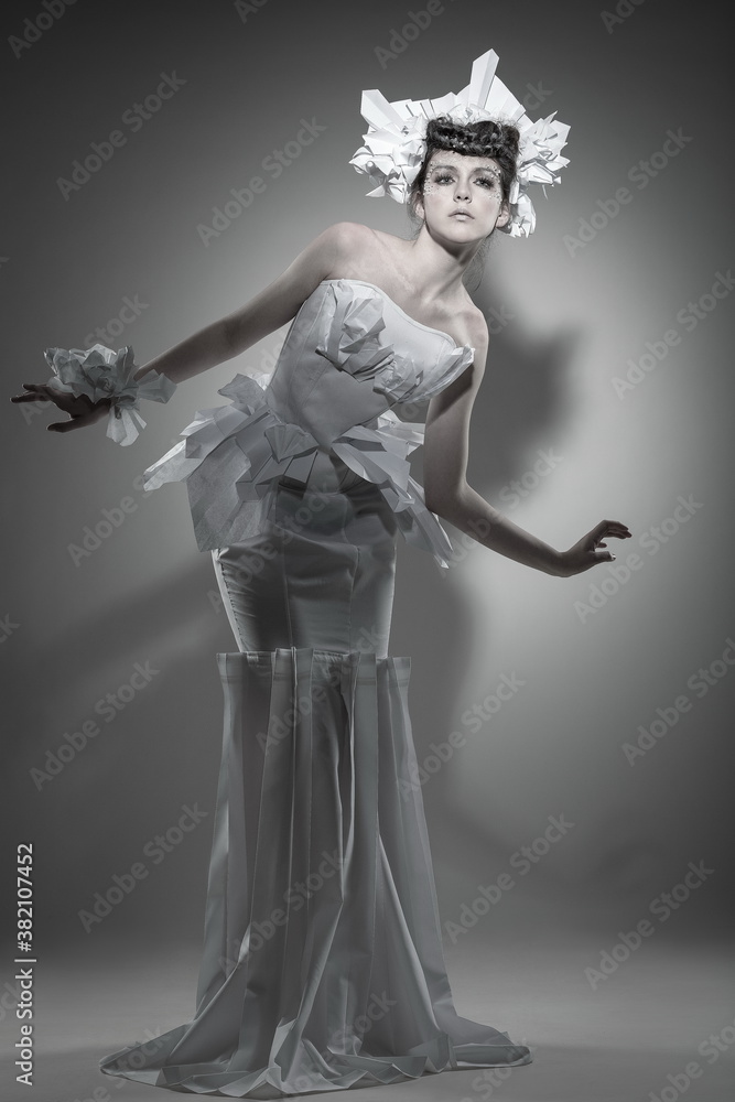 Obraz premium Young beautiful female model in a white dress on a white background with a shadow