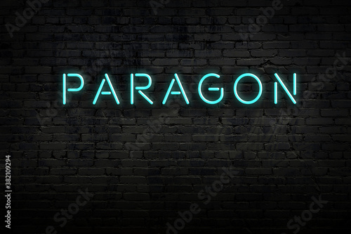Night view of neon sign on brick wall with inscription paragon