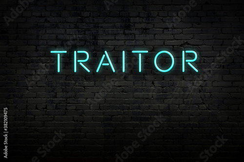Photo Neon sign. Word traitor against brick wall. Night view