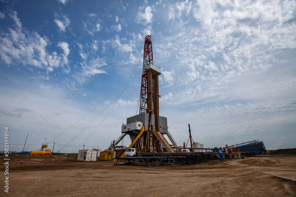 Oil drill rig in field. Blue sky with clouds. Uralsk region, Kazakhstan. Oil drill rig in field. Blue sky with clouds. Uralsk region, Kazakhstan.