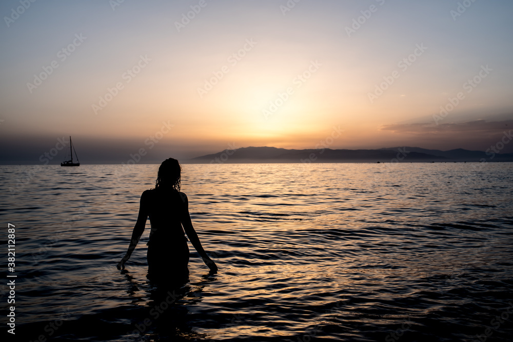 Young woman bathing in the sea in a sunset
