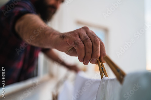 Close up of a man hanging his clothes using wooden clothespins