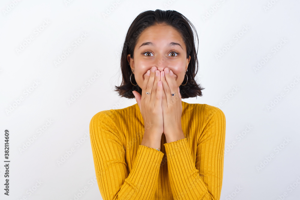 Vivacious Young hispanic girl with short hair wearing casual yellow sweater isolated over giggles joyfully, covers mouth, has fun alone, has natural laughter, hears positive story or funny anecdote Vivacious Young hispanic girl with short hair wearing casual yellow sweater isolated over giggles joyfully, covers mouth, has fun alone, has natural laughter, hears positive story or funny anecdote