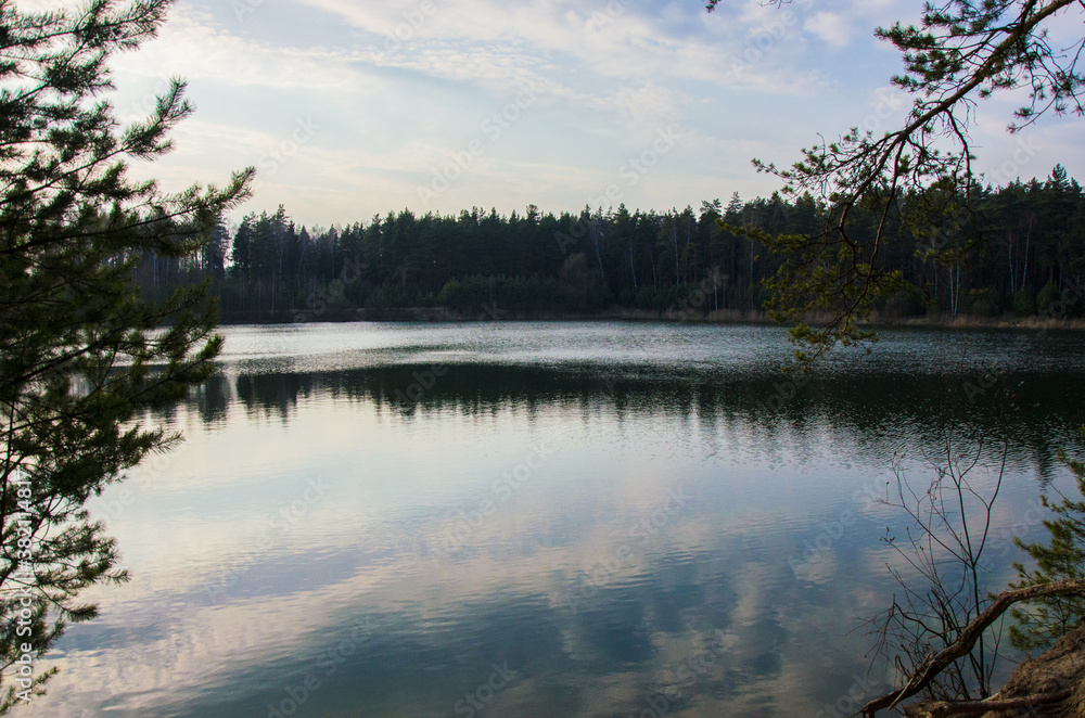 Fototapeta premium a picturesque forest lake with banks covered with coniferous forest in early spring