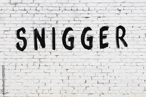 Valokuva White wall with black paint inscription snigger on it