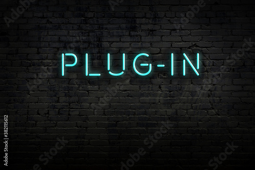 Night view of neon sign on brick wall with inscription plug-in