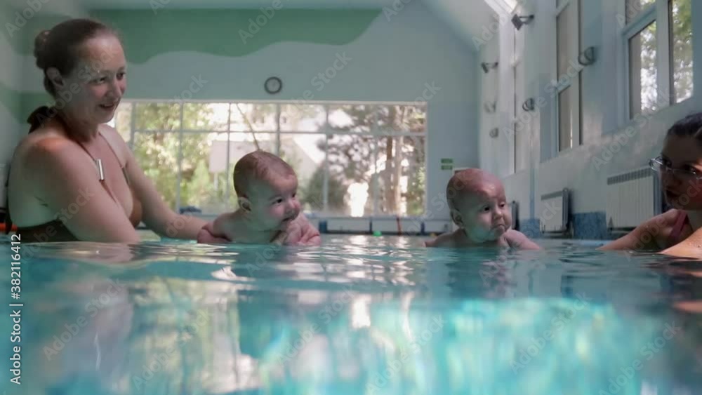 Mom teaches a little child to swim underwater in water baby class in the pool Mom teaches a little child to swim underwater in water baby class in the pool