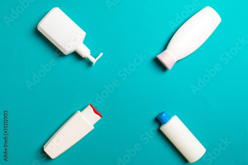 Set of White Cosmetic containers isolated on colored background, top view with copy space. Group of plastic bodycare bottle containers with empty space for you design