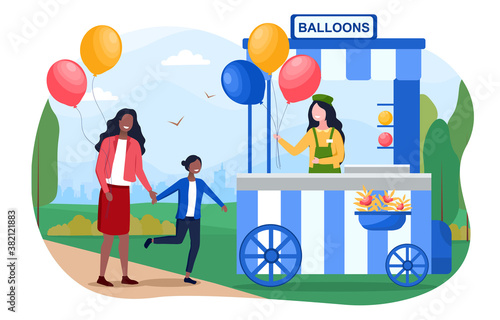 Mom and daughter buying baloons, from a street vendor at a fair.