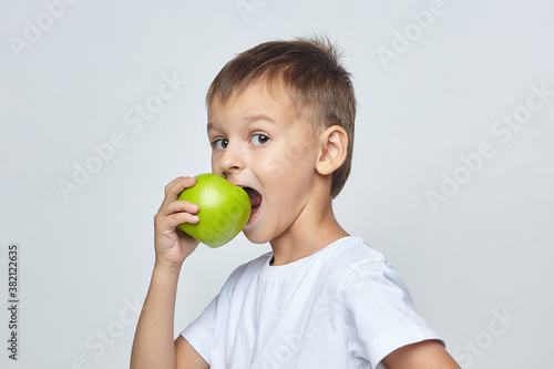 cute boy bites a green Apple. photo session in the Studio on a white background