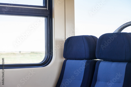 Empty seats in a modern regional train, European style, on a travel in a countryside with a speed blur effect seen from the window