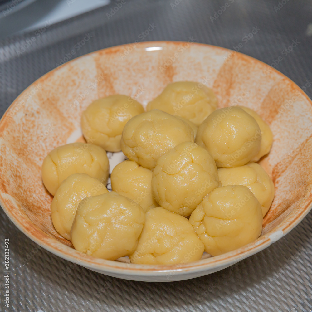 Fresh raw dough balls in a brown ceramic bowl on a metal base, preparation of tortillas or empanadas in traditional Mexican cuisine
