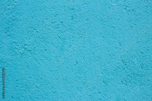 Clean cement wall painted bright blue full of small holes with space to input a text.