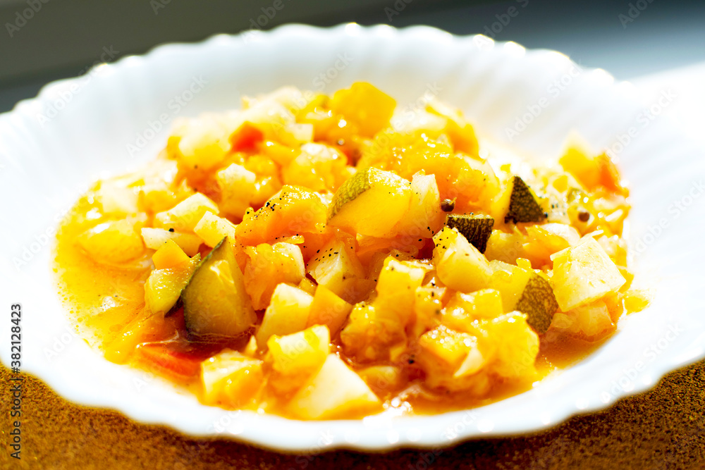 Mix of stewed vegetables on a white plate in cafe. Cooked vegan or vegetarian food. Mix of stewed vegetables on a white plate in cafe. Cooked vegan or vegetarian food.