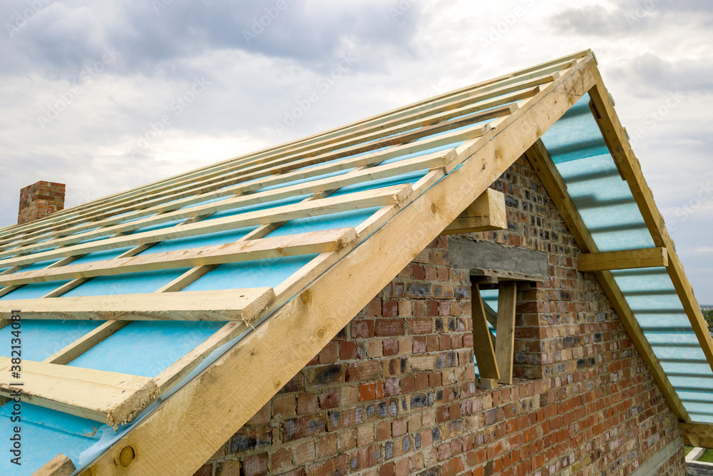 Obraz premium Aerial view of a brick house with wooden roof frame under construction.