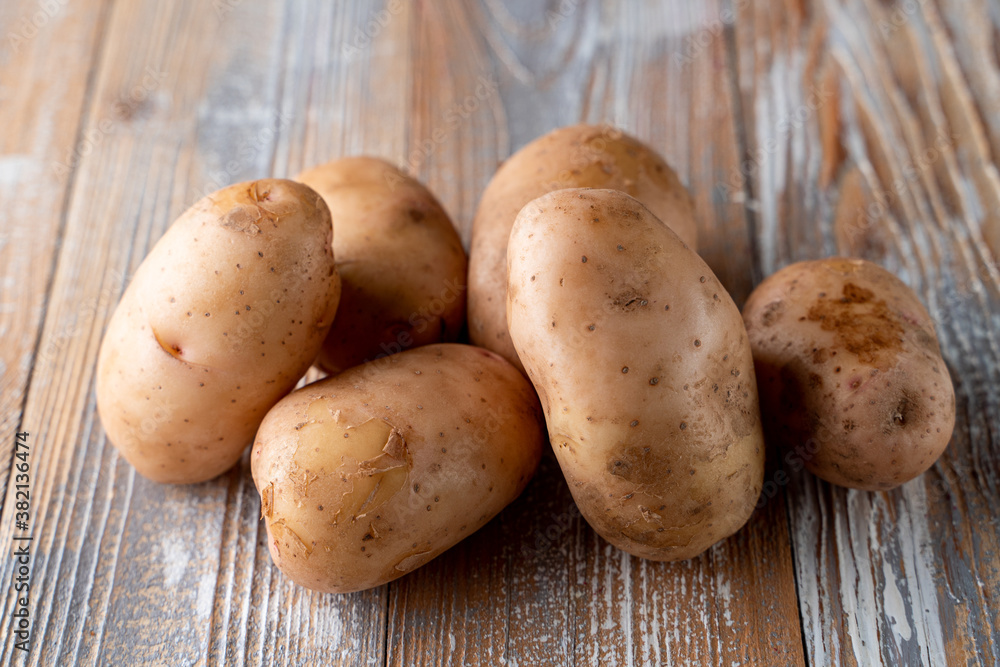 Raw unpeeled potatoes on light wooden table Raw unpeeled potatoes on light wooden table