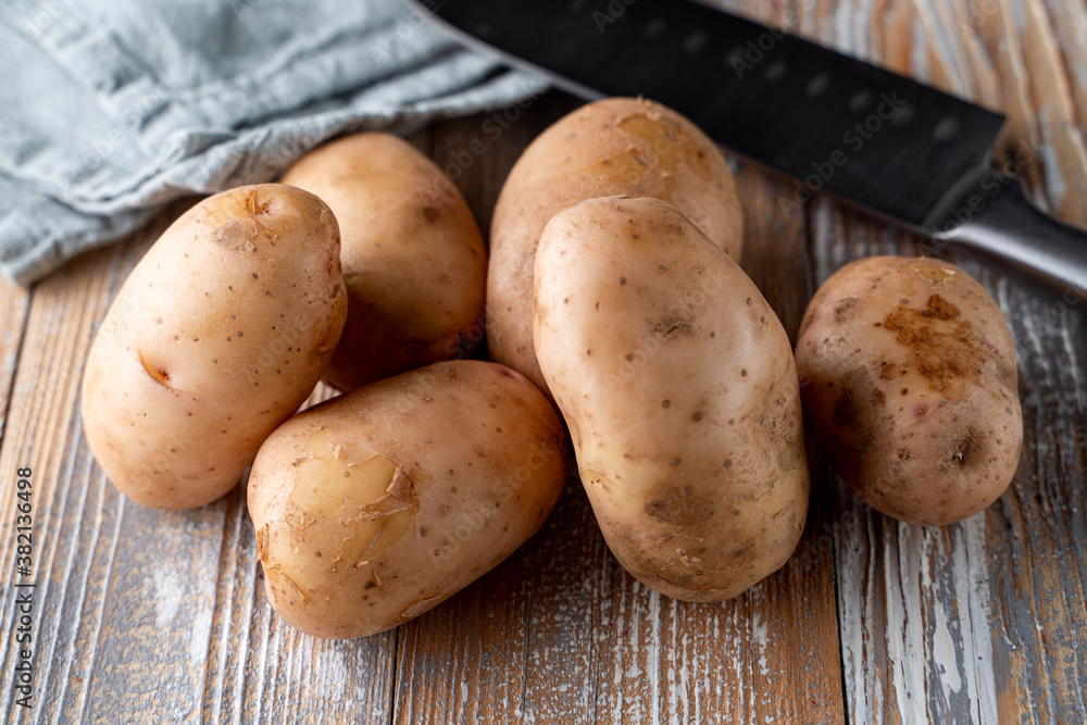 Raw unpeeled potatoes on light wooden table Raw unpeeled potatoes on light wooden table