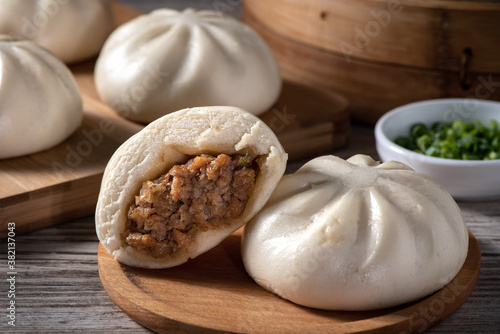 Delicious baozi, Chinese steamed meat bun is ready to eat on serving plate and steamer, close up, copy space product design concept.