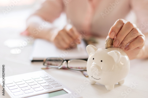 Old women's hands put money coins in a piggy Bank, the concept of retirement, savings, old age.