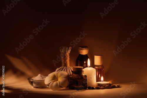 Beautiful spa composition with candles, frangipani flower, oil flasks, bowl with salt and herbal ball.