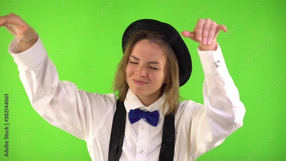 Beautiful Woman in a black hat, white shirt, bow tie and suspender Dances on a Green Background, Chromakey. Great Mood Concept. Beautiful Woman in a black hat, white shirt, bow tie and suspender Dances on a Green Background, Chromakey. Great Mood Concept.