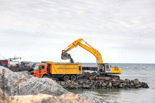 The excavator is loading excavation to dump truck. Modern hydraulic excavators come in a wide variety of sizes. The smaller ones are called mini or compact excavators.